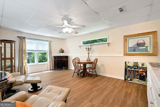 living room featuring a drop ceiling, light hardwood / wood-style flooring, and ceiling fan