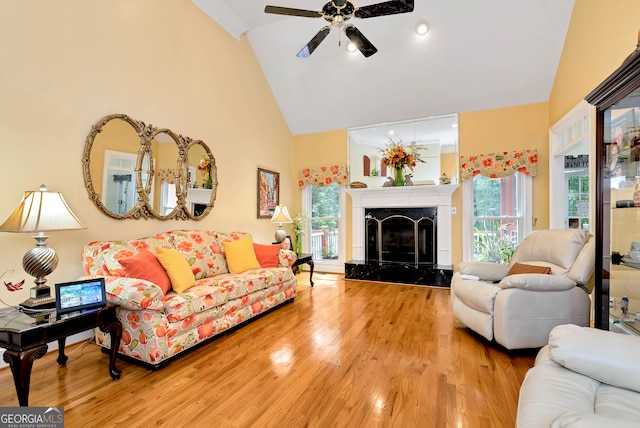 living room featuring a fireplace, light hardwood / wood-style floors, high vaulted ceiling, and ceiling fan