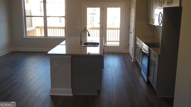 kitchen with sink, stainless steel electric range, a healthy amount of sunlight, and stone counters