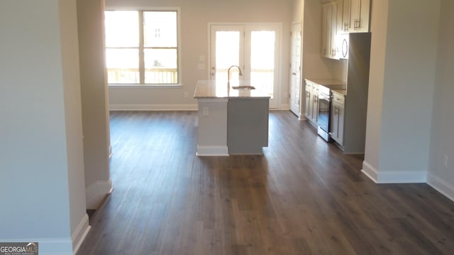 kitchen featuring stainless steel appliances, dark hardwood / wood-style flooring, light stone countertops, and sink