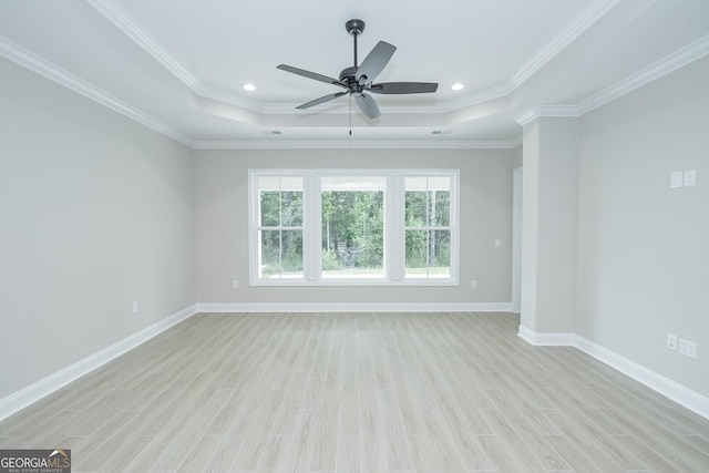 unfurnished room featuring a raised ceiling, light wood-type flooring, and crown molding