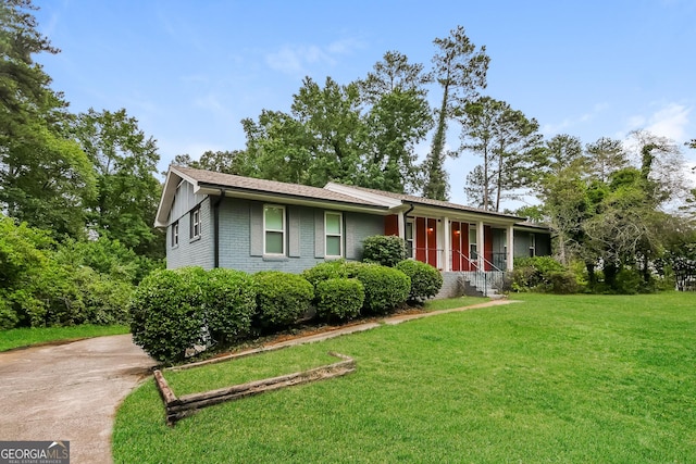 ranch-style home with concrete driveway, brick siding, and a front lawn