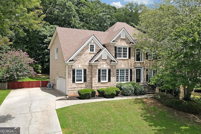 view of front of house with a front yard, central air condition unit, and a garage