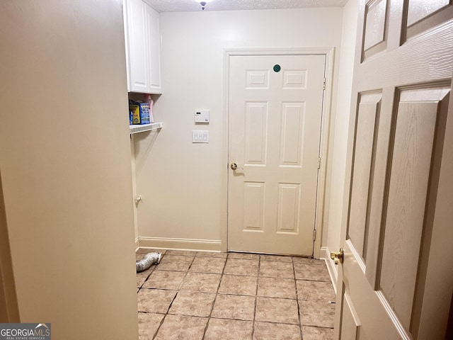 washroom with cabinets, a textured ceiling, and light tile patterned flooring