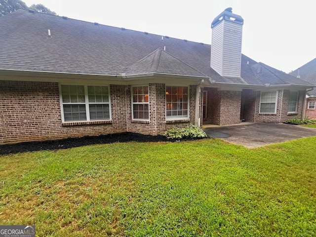 rear view of house featuring a yard and a patio