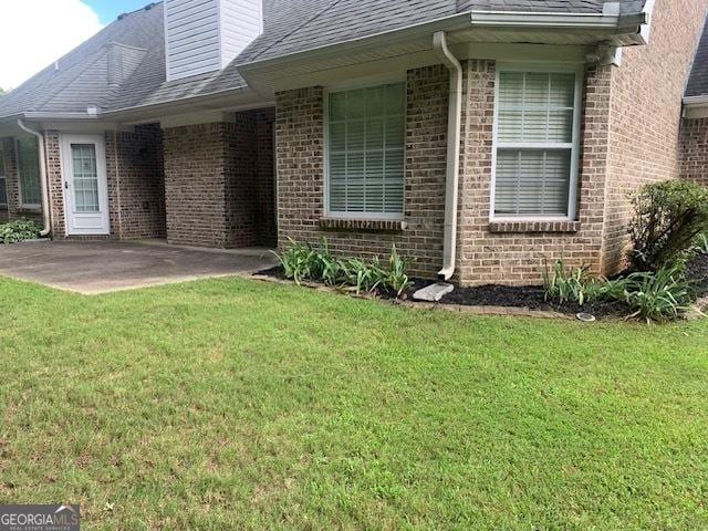 doorway to property with a patio area and a lawn