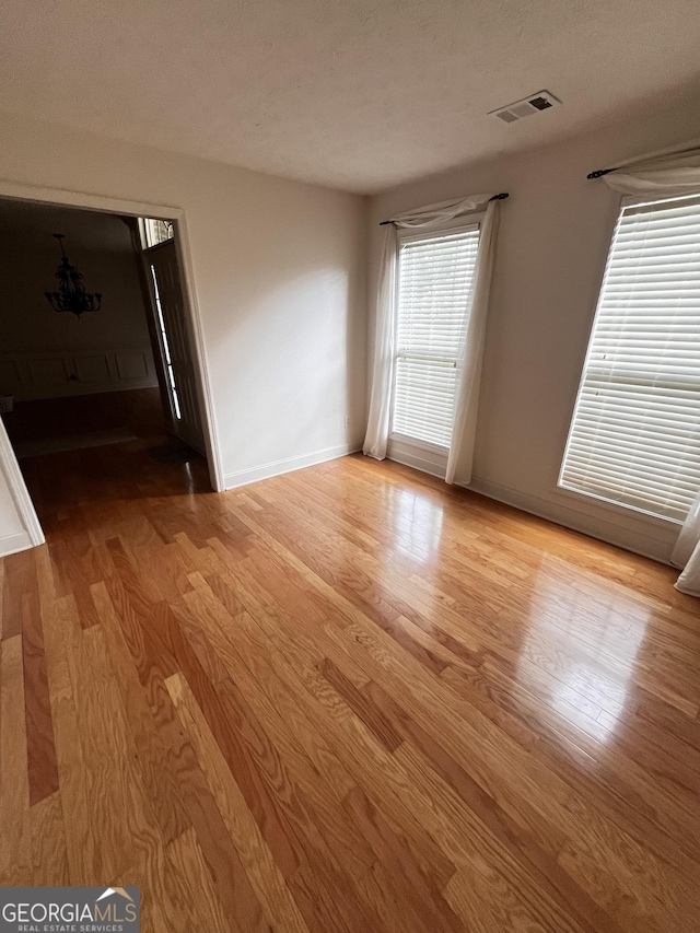 spare room featuring a textured ceiling and light hardwood / wood-style flooring