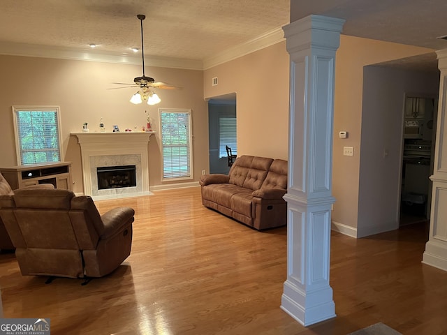 living room featuring ornate columns, crown molding, hardwood / wood-style flooring, and a fireplace