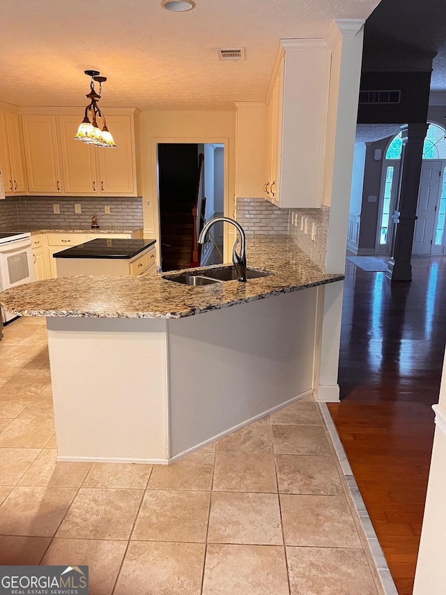 kitchen with pendant lighting, white range with electric stovetop, sink, white cabinets, and kitchen peninsula