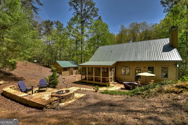 rear view of house featuring a storage unit, an outdoor fire pit, and a sunroom