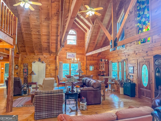 living room featuring a ceiling fan, lofted ceiling with beams, wooden walls, and light wood-style flooring