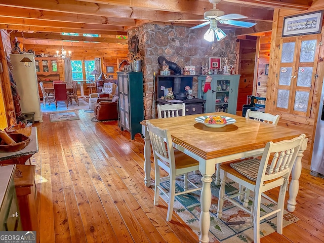 dining room with beam ceiling, light wood-style floors, and a wood stove