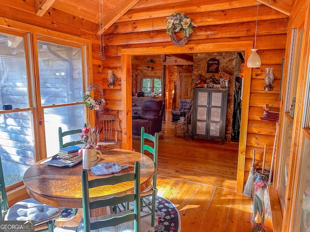 dining area featuring wood-type flooring, vaulted ceiling with beams, log walls, and wooden ceiling