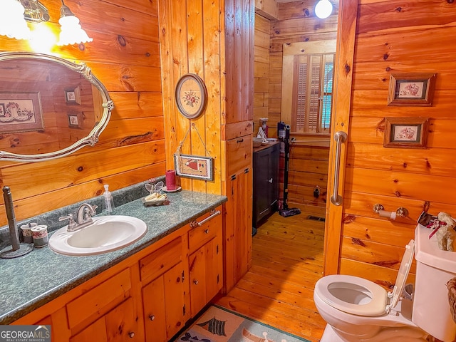 bathroom featuring toilet, vanity, and wooden walls