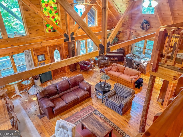 living room with high vaulted ceiling, wood walls, a ceiling fan, and wood-type flooring