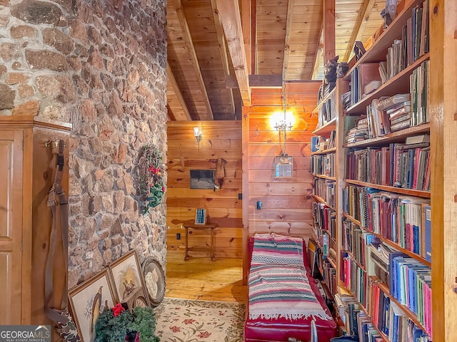 sitting room with wood ceiling, wooden walls, beamed ceiling, and wood finished floors