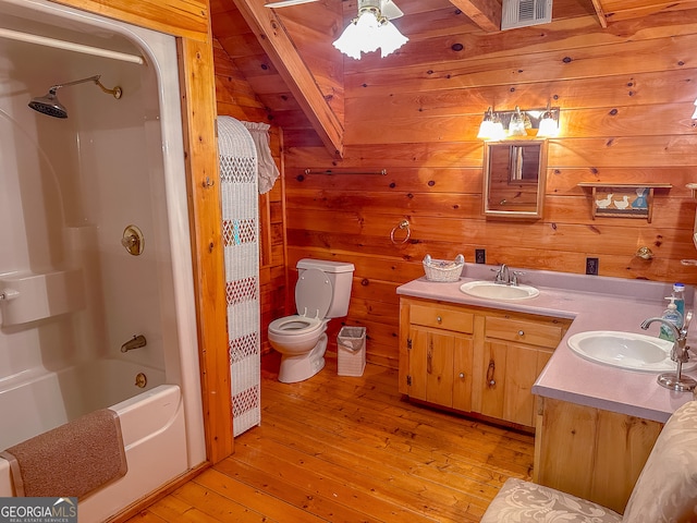 full bathroom with wood walls, toilet, vanity, shower / tub combo with curtain, and hardwood / wood-style flooring