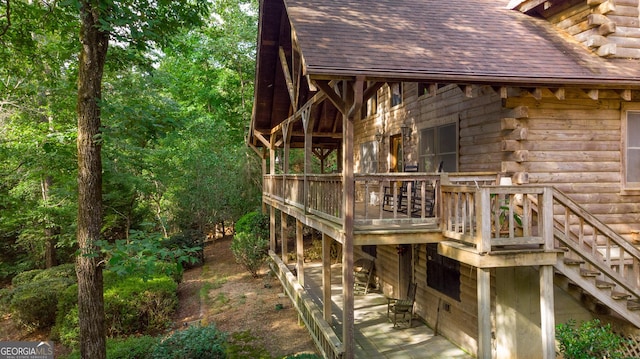 view of side of property with a shingled roof, stairway, and log exterior
