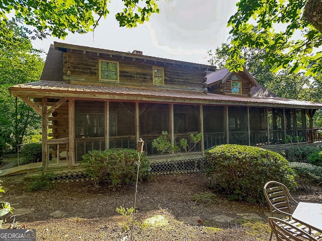 rear view of house featuring log siding, a sunroom, and metal roof