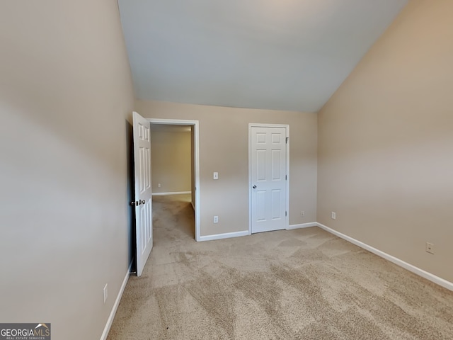 unfurnished bedroom with lofted ceiling and light colored carpet