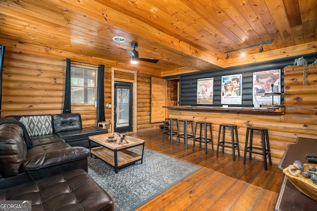 living room featuring log walls, hardwood / wood-style flooring, wood ceiling, rail lighting, and ceiling fan