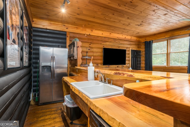 kitchen with stainless steel fridge with ice dispenser, sink, dark wood-type flooring, log walls, and track lighting