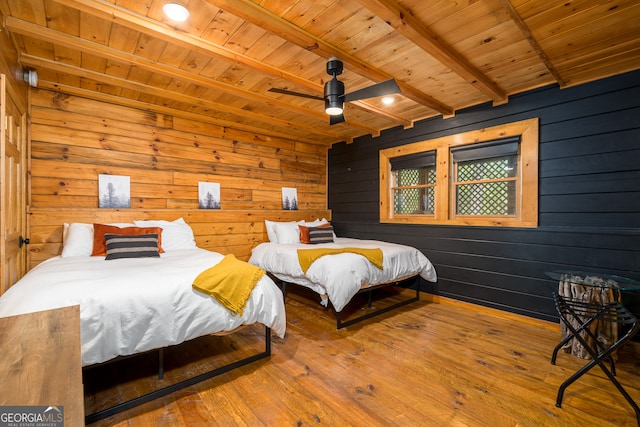 bedroom with ceiling fan, wooden ceiling, hardwood / wood-style floors, beamed ceiling, and wood walls