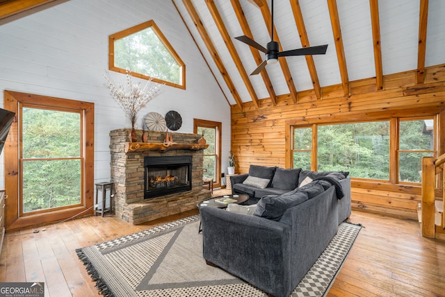 living room with a healthy amount of sunlight, beamed ceiling, light wood-type flooring, and high vaulted ceiling