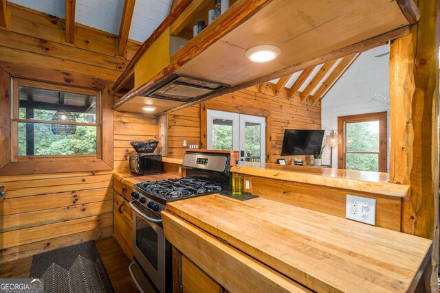 kitchen with gas range, hardwood / wood-style flooring, vaulted ceiling with beams, wood walls, and wood counters