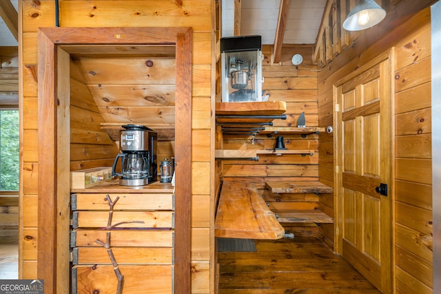 interior space with vaulted ceiling, wooden walls, and hardwood / wood-style floors