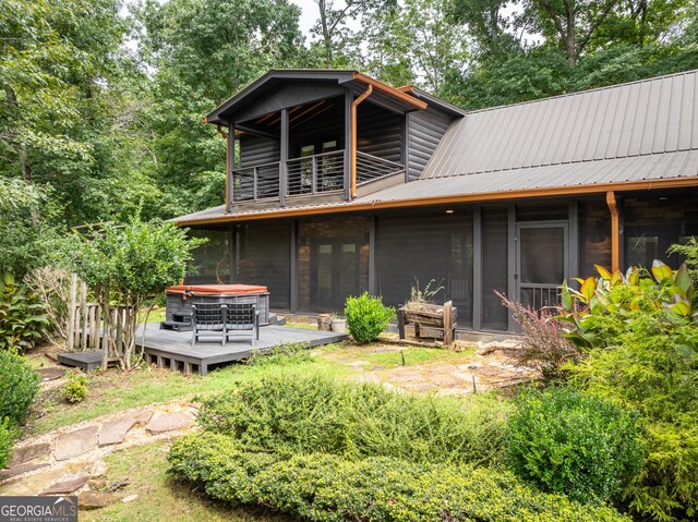 rear view of house with a balcony, a wooden deck, and a sunroom