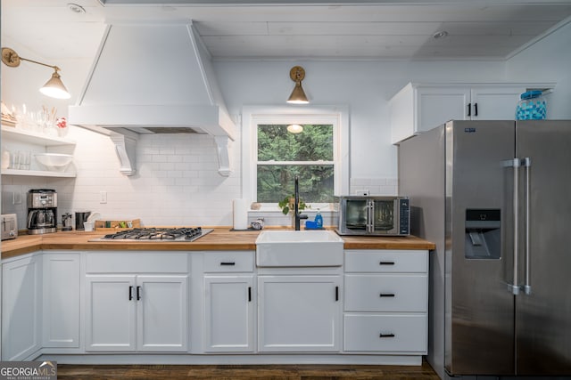 kitchen with decorative backsplash, pendant lighting, custom range hood, and appliances with stainless steel finishes