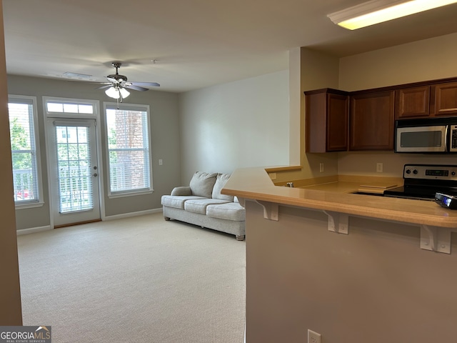 kitchen with a kitchen breakfast bar, light carpet, ceiling fan, stainless steel appliances, and kitchen peninsula