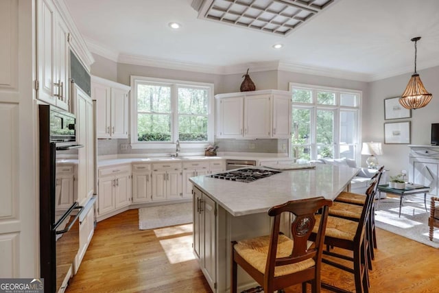 kitchen with pendant lighting, light hardwood / wood-style floors, a kitchen island, and a wealth of natural light