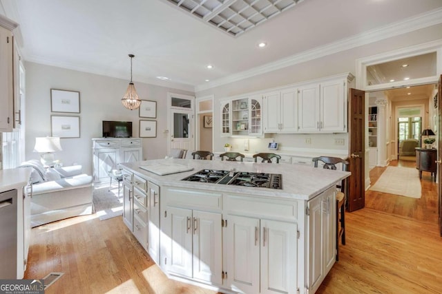 kitchen featuring a center island, white cabinetry, light hardwood / wood-style flooring, and crown molding