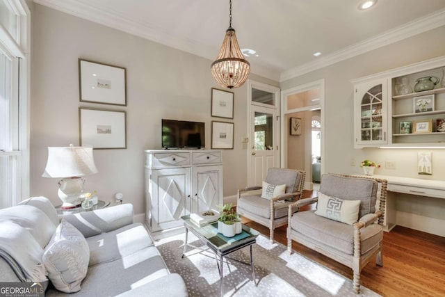 living room featuring light hardwood / wood-style floors, ornamental molding, and a chandelier