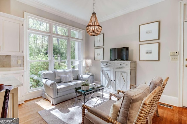 living area featuring baseboards, ornamental molding, visible vents, and light wood-style floors