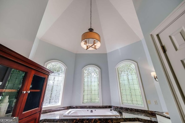 bathroom featuring vaulted ceiling and a bath