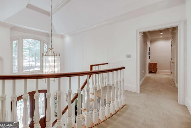 hall featuring an inviting chandelier, carpet, a tray ceiling, and ornamental molding