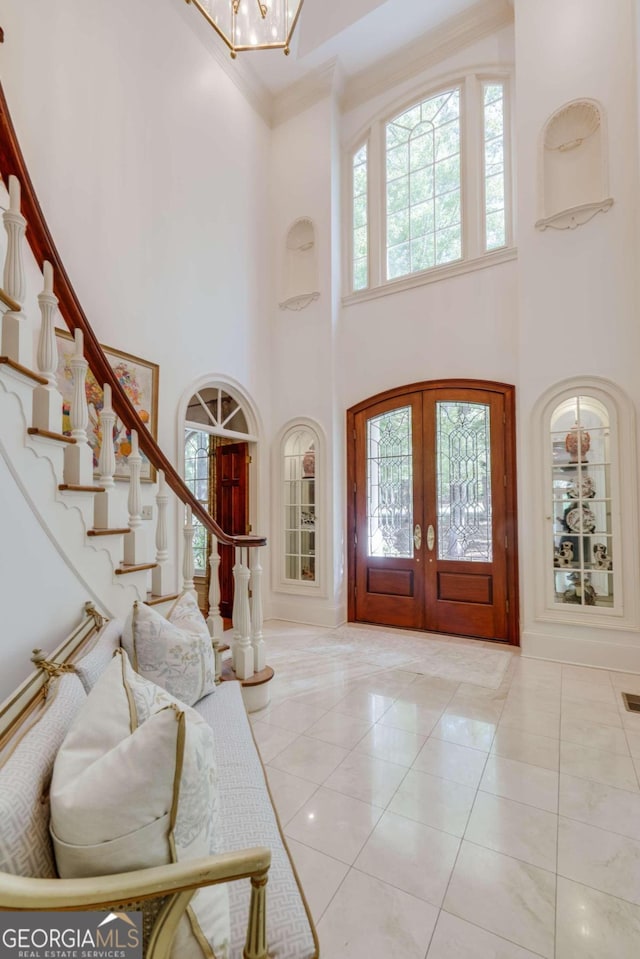 entrance foyer with plenty of natural light, a high ceiling, french doors, and light tile patterned floors