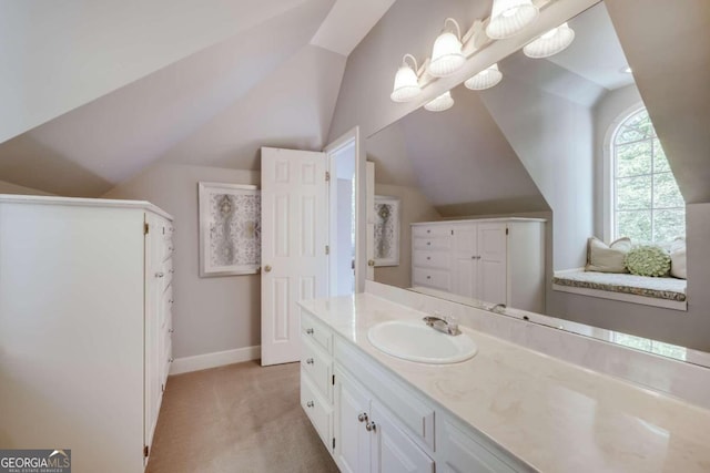 bathroom with vaulted ceiling, a notable chandelier, vanity, and baseboards