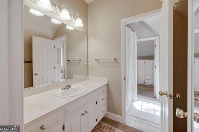 bathroom featuring tile patterned floors, vanity, and vaulted ceiling