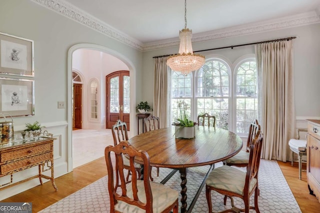 dining area with light hardwood / wood-style floors, ornamental molding, and an inviting chandelier