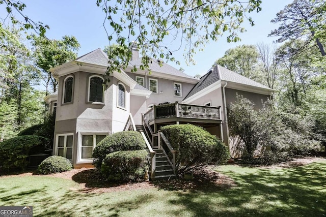 view of front facade featuring a chimney, stucco siding, stairway, a deck, and a front lawn