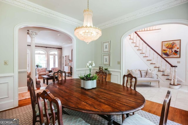 dining space with arched walkways, a notable chandelier, wood finished floors, stairs, and ornamental molding