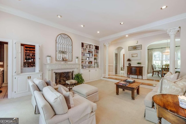 living room with light carpet, built in shelves, crown molding, and ornate columns