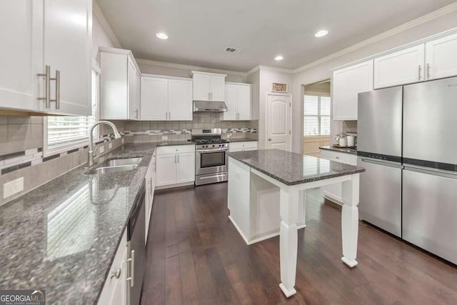 kitchen with sink, dark stone countertops, appliances with stainless steel finishes, white cabinets, and backsplash