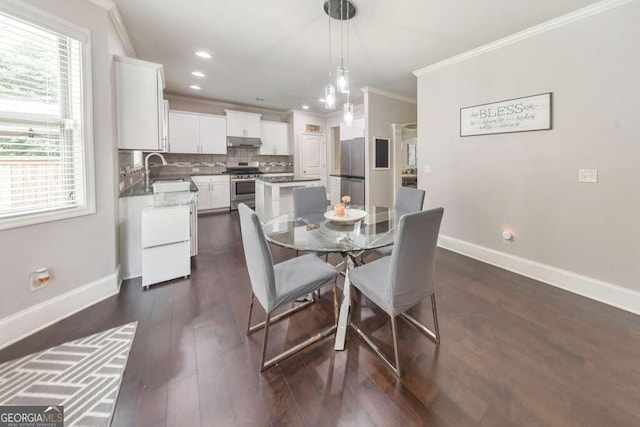 dining space featuring crown molding, sink, a wealth of natural light, and dark hardwood / wood-style floors