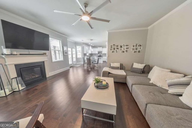 living room with dark wood-type flooring, ornamental molding, and ceiling fan