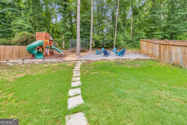 view of playground featuring a yard, a trampoline, and a fire pit